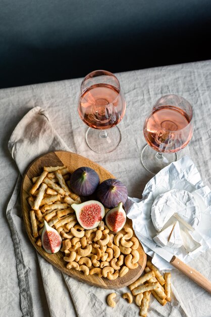 Photo rose wine with ripe figs camembert cheese and cashews on a table indoors