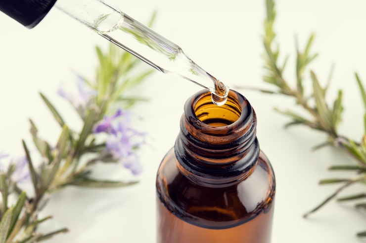 Photo rosemary essential oil. close up of a pipette, amber bottle and rosemary branch at white surface. herbal remedies