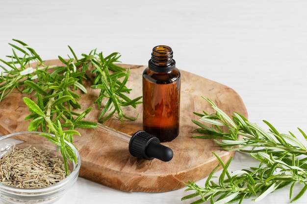 rosemary essential oil and fresh rosemary branch on wooden background