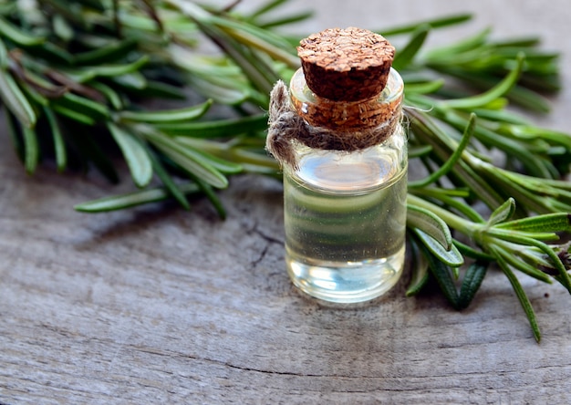 Rosemary essential oil in a glass bottle and rosemary leaves