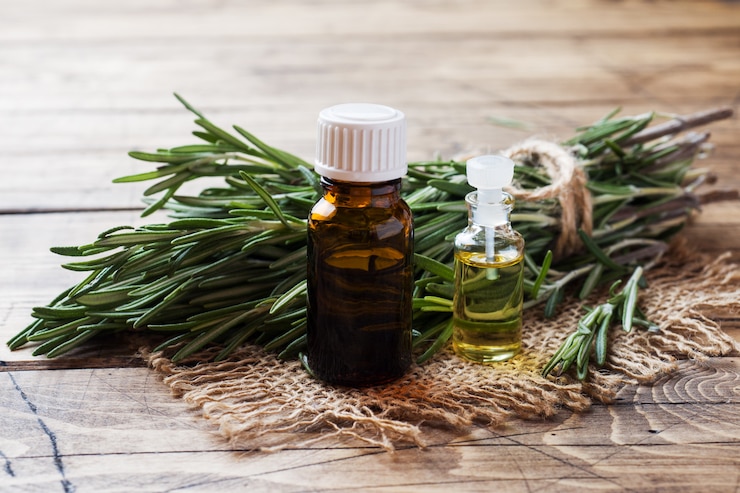 Photo rosemary essential oil in a glass bottle with fresh branch rosemary herb on wooden table for spa,aromatherapy and bodycare.copy space.