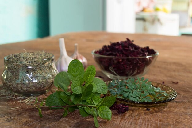 Rosemary hibiscus garlic rue and mint on brown table showing blurred kitchen in background