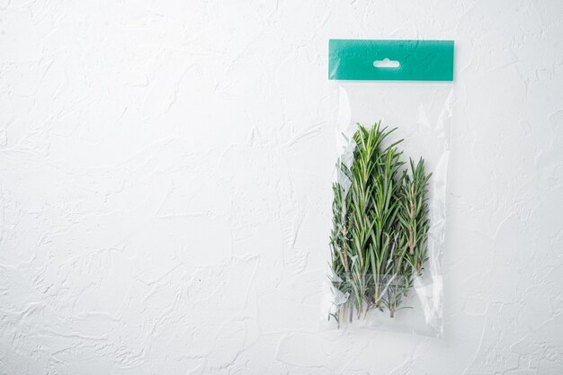 Rosemary in plastic bag set, on white table, top view flat lay