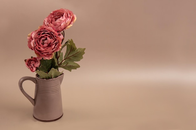 Roses in a ceramic jug on a beige background with copy space greeting card