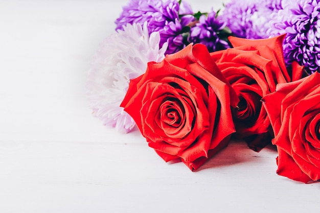 Roses and chrysanthemums on a light table Copy space closeup