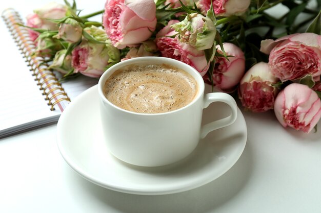 Roses, cup of coffee and copybook on white