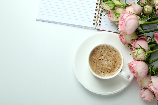 Roses, cup of coffee and copybook on white