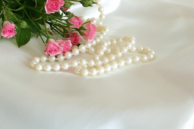 Photo roses and pearls on the white silk