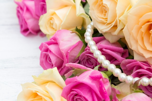  Roses and pearls on a wooden background