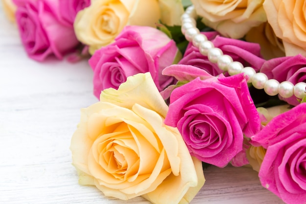  Roses and pearls on a wooden background