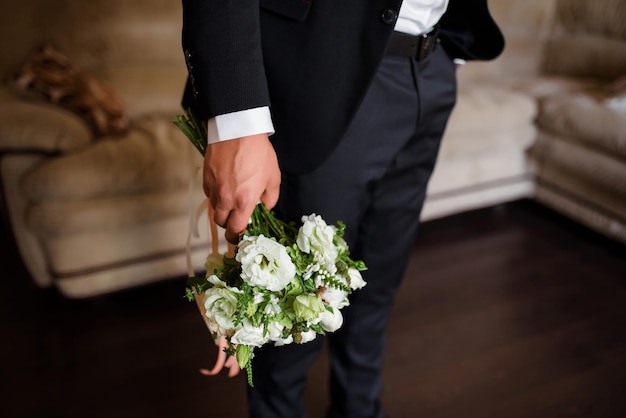 Розы и пионы в стильном свадебном букете, который жених держит в руке