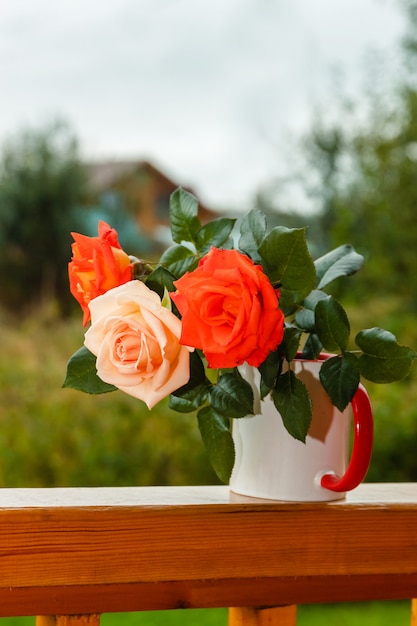 Photo roses stand on wooden porch on the background of a country house