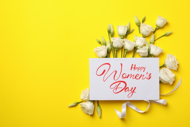 Roses, text Happy Women's Day and ribbon on yellow background