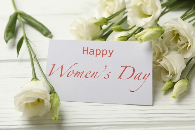 Roses and text Happy Women's Day on white wooden background