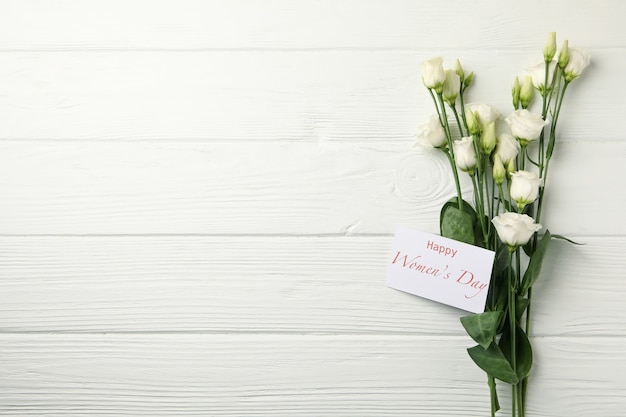 Rose e testo happy women's day su fondo di legno bianco