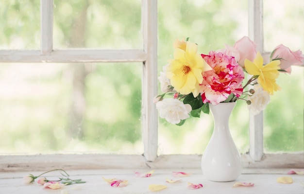 Roses in vase on old windowsill