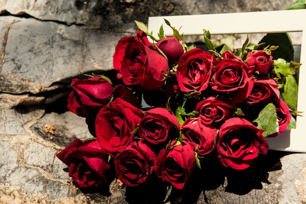 roses in white frame on stone. background of valentine day concept and love concept.