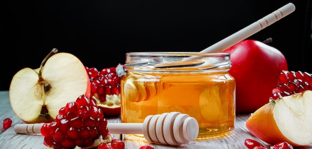 Rosh Hashanah celebration Jar with honey apples and pomegranates on dark wooden background Jewish traditional religious holiday Place for your text banner format