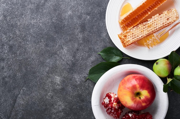 Rosh Hashanah 꿀 항아리 벌집 사과와 석류 어두운 회색 오래 된 소박한 콘크리트 배경 테이블 유대인 새해 휴일 인사말 카드 Rosh Hashanah 휴일 속성 텍스트 공간