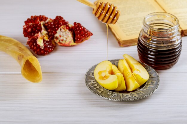 Rosh hashanah jewesh holiday concept shofar, torah book, honey, apple and pomegranate. 