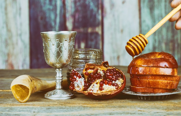 Rosh hashanah jewesh holiday shofar, torah book, honey, apple and pomegranate over wooden 