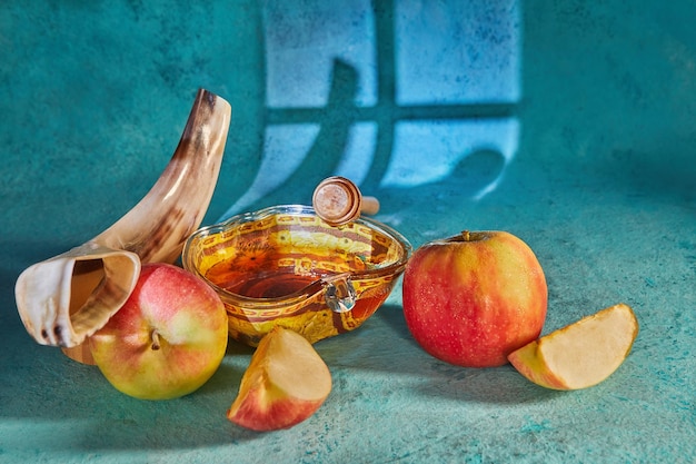 Rosh hashanah jewish new year holiday concept Appleshaped bowl with honey apples shofar are traditional symbols of the holiday