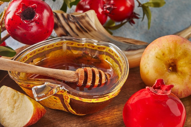 Photo rosh hashanah jewish new year holiday concept bowl in the shape of an apple with honey apples pomegranates shofar on a blue background