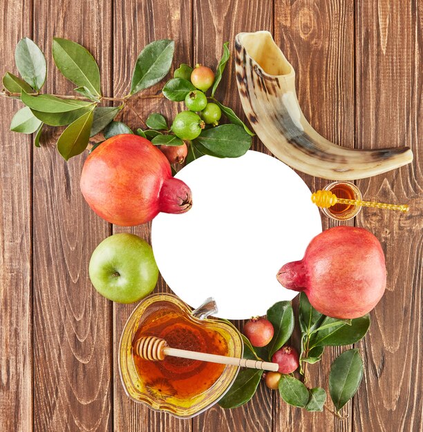 Roshhashanah-ユダヤ人の新年の休日のコンセプト。蜂蜜、ザクロ、ショファーが入ったリンゴの形をしたボウルは、休日の伝統的なシンボルです。フラットレイ。コピースペース