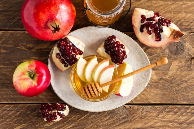 Rosh hashanah jewish New Year holiday concept. Traditional symbol. Apples, honey, pomegranate. on wooden table