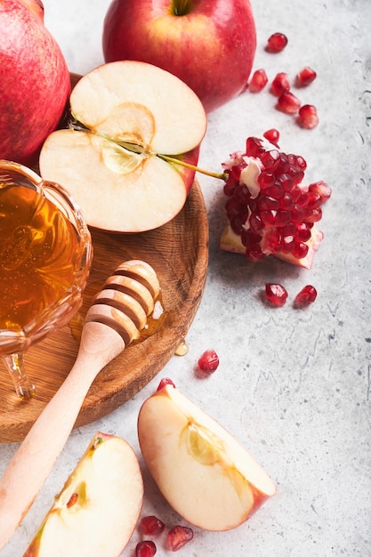 Rosh Hashanah Pomegranate apples and honey traditional products for celebration on rustic grey background Jewish Autumn Rosh Hashana celebration Jewish holiday Rosh Hashana design Selective focus