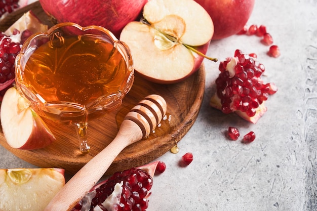 Rosh Hashanah Pomegranate apples and honey traditional products for celebration on rustic grey background Jewish Autumn Rosh Hashana celebration Jewish holiday Rosh Hashana design Selective focus