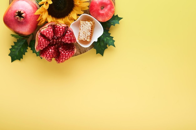 謹賀新年 熟したザクロ リンゴ蜂蜜とヒマワリの黄色の花黄色の背景にシンボル ユダヤ人の謹賀新年の休日属性トップ ビュー コピー スペース