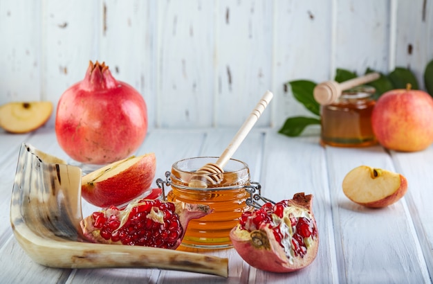 Photo rosh hashanah -traditional symbols: honey jar and fresh apples with pomegranate and shofar- horn.