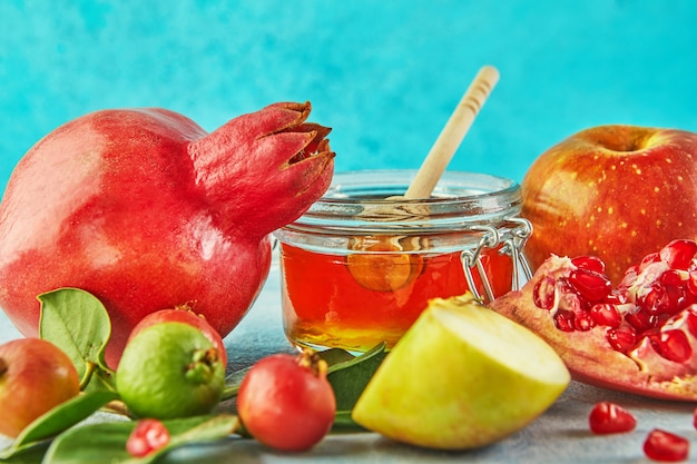 Rosh hashanah with honey jar and fresh apples with pomegranate seeds