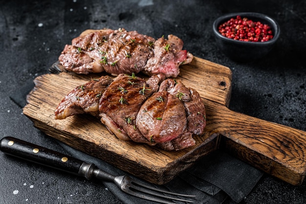 Filetto di agnello arrosto bistecche di carne di montone con spezie sfondo nero vista dall'alto