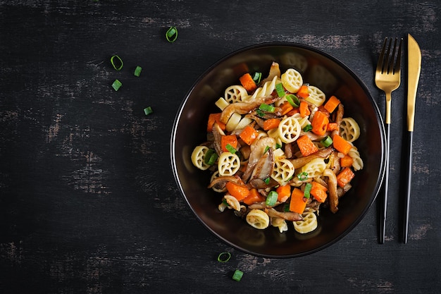 Rotelle pasta glutenvrij met champignons en pompoen op een donkere achtergrond Vegetarisch veganistisch eten Italiaanse keuken Bovenaanzicht