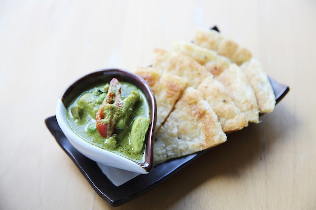 Roti with green curry on wood background