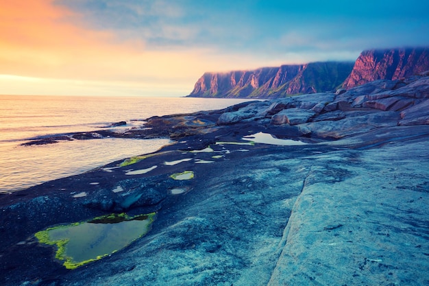 Rotsachtig strand bij magische zonsondergang Wilde natuur van Noorwegen Senja Island