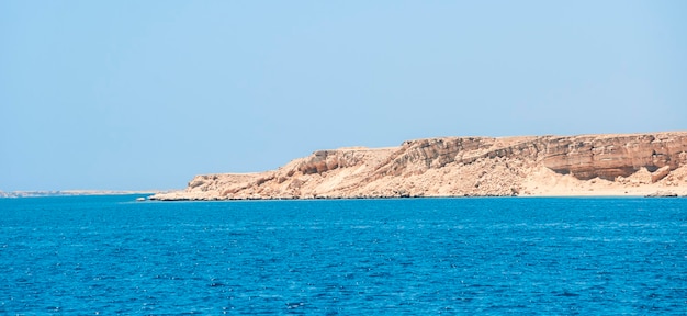 Rotsachtige kust aan zee tegen de achtergrond van een blauwe wolkenloze hemel Prachtig Egyptisch landschap