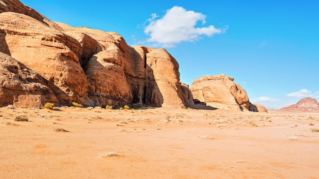 Rotsachtige massieven op rode zandwoestijn, heldere blauwe hemel op achtergrond - typisch landschap in Wadi Rum, Jordan