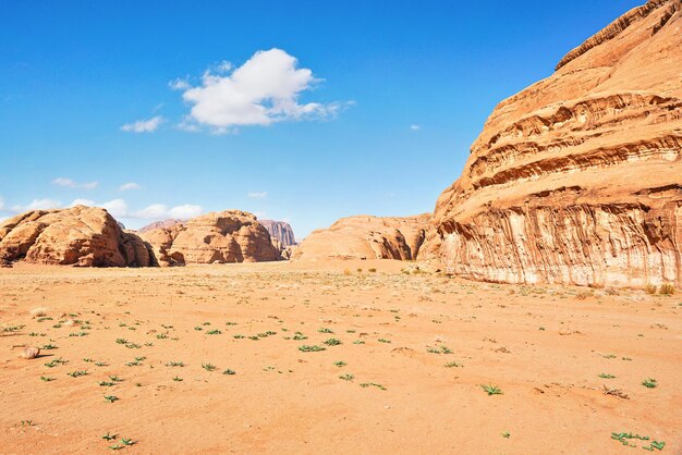 Rotsachtige massieven op rode zandwoestijn, heldere blauwe hemel op achtergrond - typisch landschap in Wadi Rum, Jordan