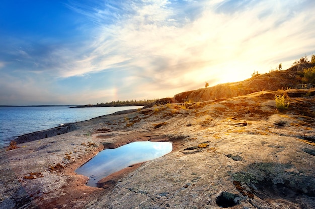 Foto rotsachtige oever van het meer met een plas die de lucht weerkaatst