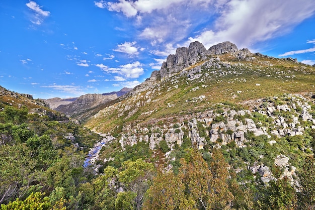 Foto rotsachtige tafelberg met bomen en gras onder een bewolkte blauwe lucht met copyspace serene kalme helling zonder mensen in een vredige natuurlijke omgeving top is gelegen in west-kaap, zuid-afrika