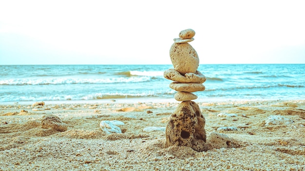 Foto rotsen evenwichtig op schoon zand met strandachtergrond die het concept harmonie tonen