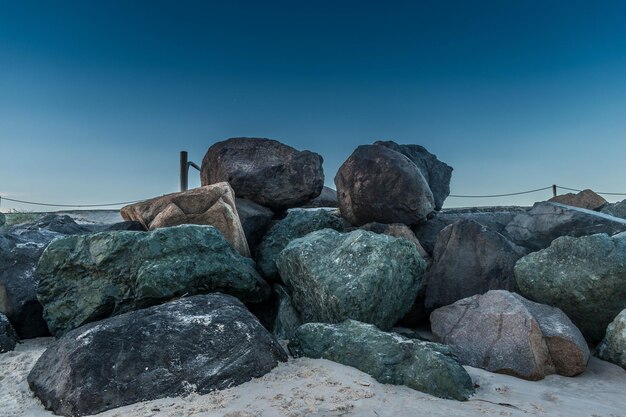 Foto rotsen op het strand tegen een heldere blauwe hemel