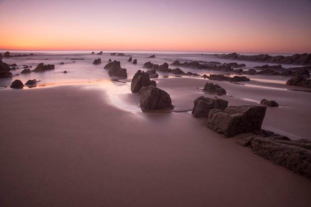 rotsformaties op het strand bij zonsonderganglicht