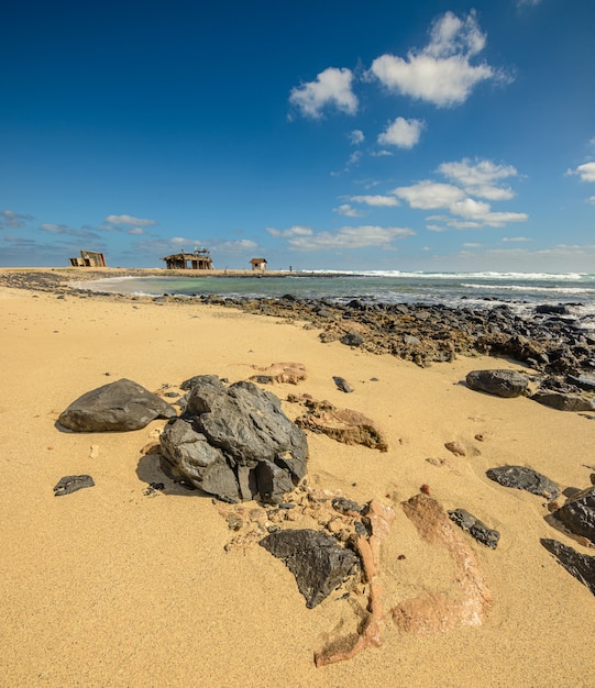 rotszandstrand op Kaapverdië met hutten in de verte