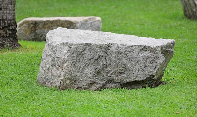 Rotszetel op groene grastuin. Natuurstenen stoel in park.