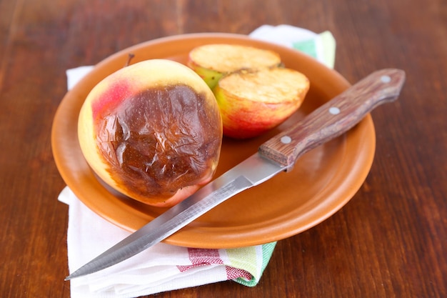 Rotten apples on plate on table