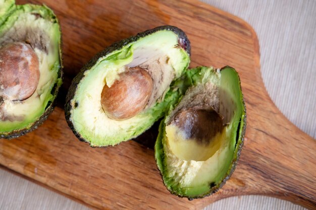 Rotten avocado cut in half on wooden backgroundclose up